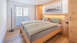 Un dormitorio con una cama, una lámpara de pie, un cuadro en la pared y una ventana.