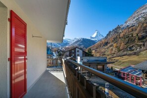 A balcony with a red door, overlooking a mountain landscape with a snow-capped peak. - Apartment Bergliebe (Zermatt)