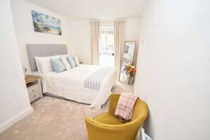 Une chambre à coucher avec un lit, une table de chevet, une chaise, un miroir et un tableau accroché au mur.