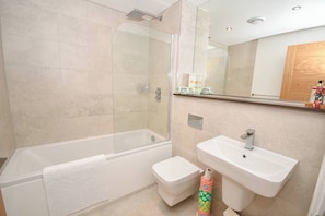 Ein modernes Badezimmer mit einer gläsernen Duschkabine, einer weißen Badewanne, einer Toilette und einem Waschbecken.