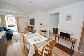A modern living room with a dining area, a sofa, a television, and a microwave. - Modern 1 Bed Apartment in Central Leeds - Sleeps 3 (Leeds)