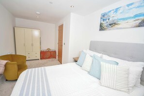 Ein Schlafzimmer mit Bett, Kleiderschrank, Stuhl und einem Bild an der Wand.