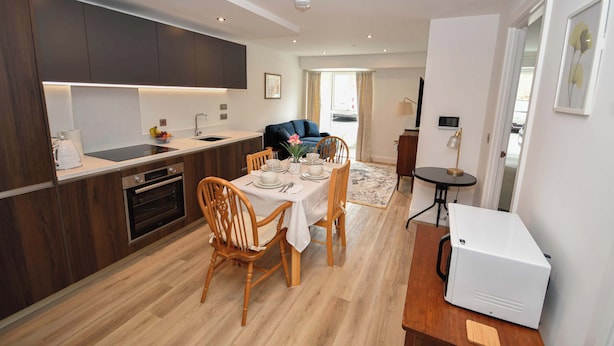 Une cuisine moderne avec un coin repas, un plancher en bois et un réfrigérateur blanc.