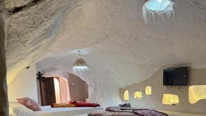 Een interieur met een bed, een televisie en een hanglamp.