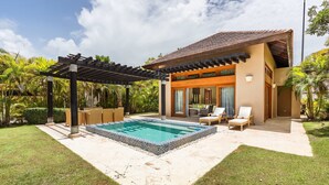 Ein modernes Haus mit Swimmingpool, Sitzgelegenheiten im Freien und einer Pergola.