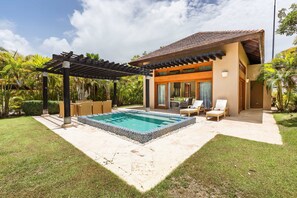 Ein modernes Haus mit Swimmingpool, Sitzgelegenheiten im Freien und einer Pergola.