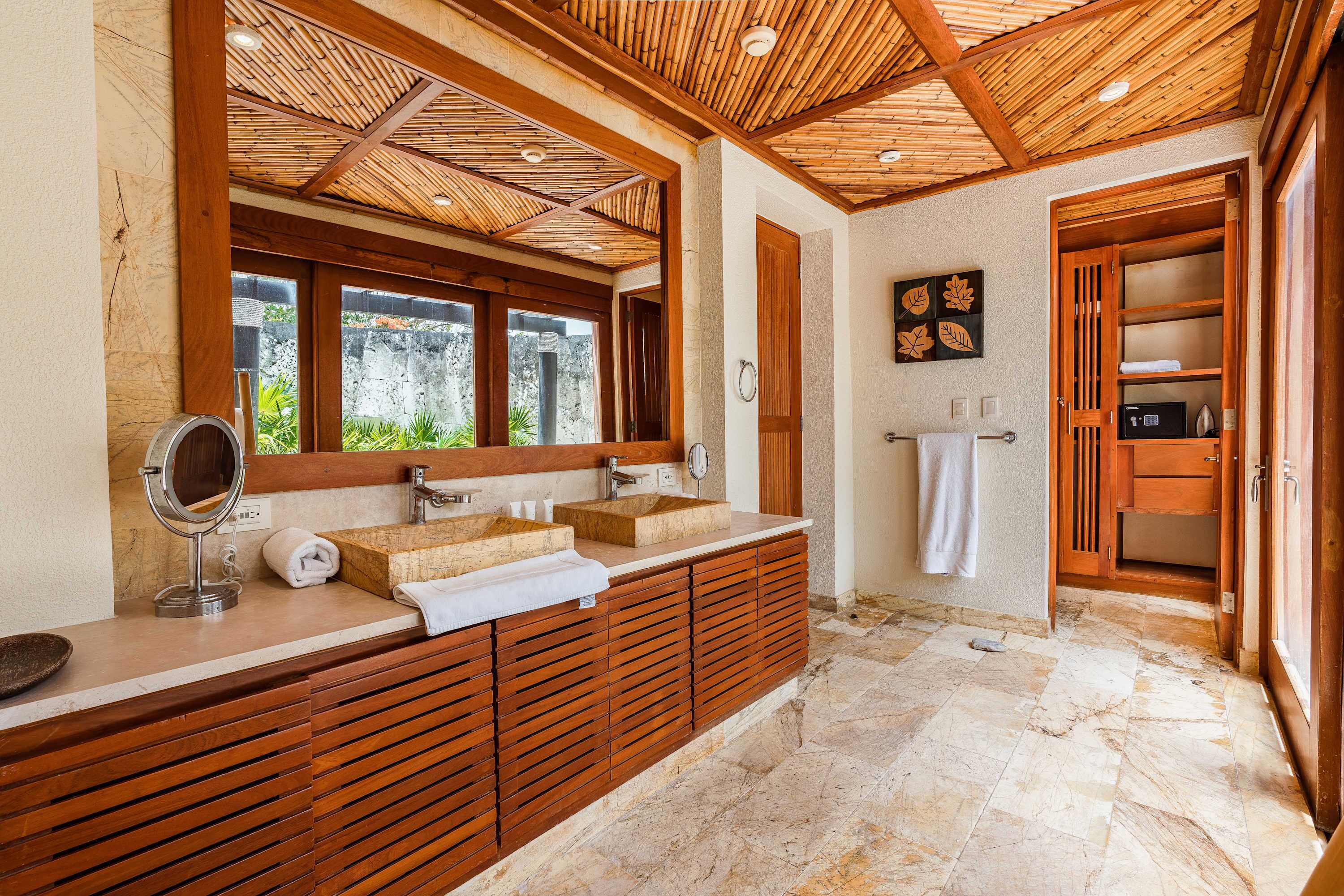 Ein Badezimmer mit einem Holzbadezimmermöbel, zwei Waschbecken, einem Spiegel und einem Handtuchhalter.