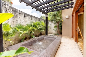A spa area with a hot tub, surrounded by plants and a pergola. - Stylish Bungalow! at Green Village with pool Ab3 (Punta Cana)