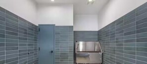 Ein Badezimmer mit Tür, Waschbecken und gefliesten Wänden.