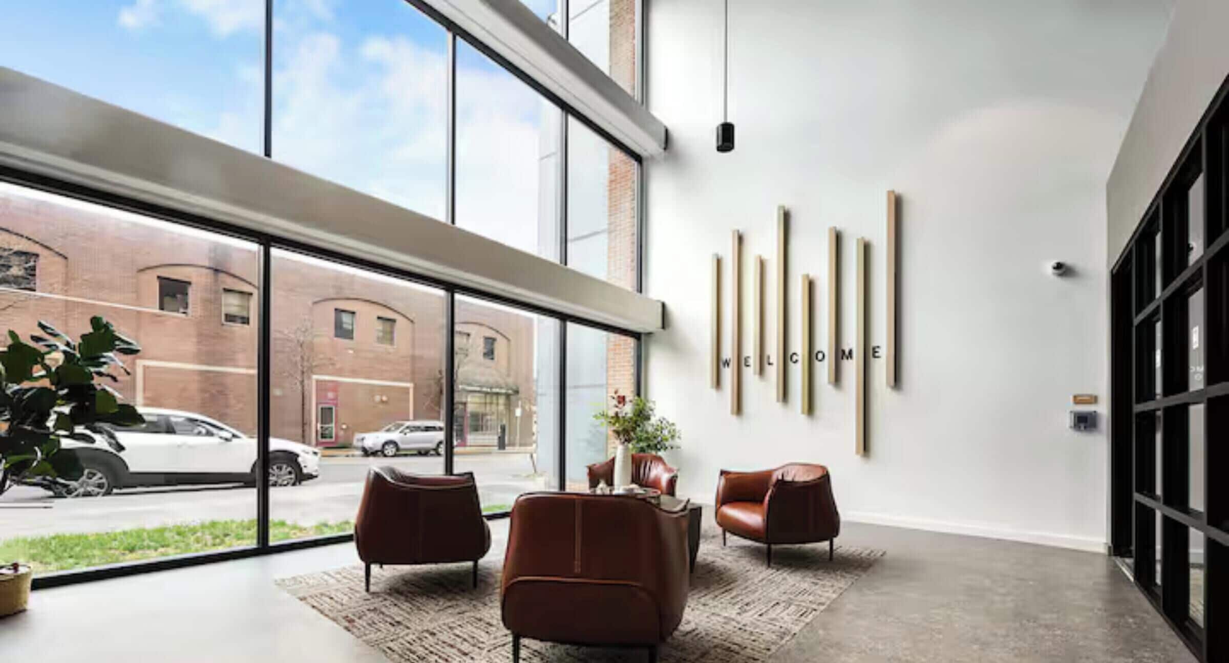 A modern interior with large windows, a brick wall, and a 'WELCOME' sign.