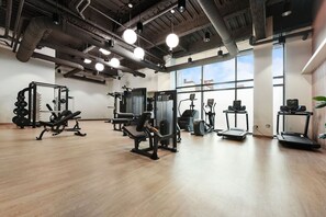 Ein Fitnessstudio mit unterschiedlichen Trainingsgeräten, großen Fenstern und einem Holzboden.