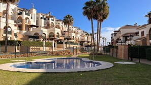 A residential building with multiple balconies, a swimming pool, and palm trees. - Quiet 2-bedroom chalet in Vera Playa | Pool & Near the beach (Vera)