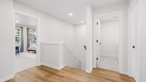 A room with a wooden floor, white walls, and a door leading to another room. - Evergreen Home - King Bed · Office Room · Near PDX (Gresham)