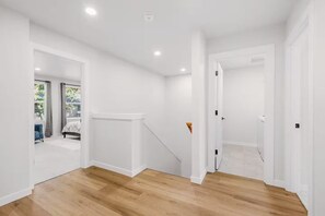 Ein Zimmer mit Holzboden, weißen Wänden und einer Tür zu einem anderen Raum.