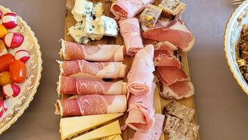 Une grande planche en bois sur laquelle sont disposés différents types de fromages, de charcuteries et de pâtés.
