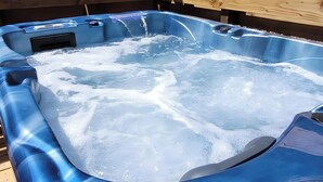 A hot tub with a smooth, reflective surface and a wooden deck surrounding it. - “Cézallier Room” Guest Suite with Private Terrace and Jacuzzi (Soulages)