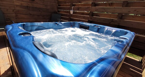 A hot tub with a wooden deck surrounding it.