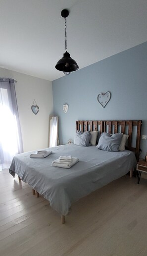 A bedroom with a bed, pillows, a nightstand, a wall-mounted light fixture, and heart-shaped decorations.