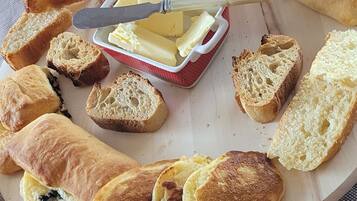 A breakfast platter with various pastries and a knife with butter on a plate.