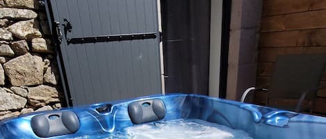 A hot tub with a built-in seat and a control panel.