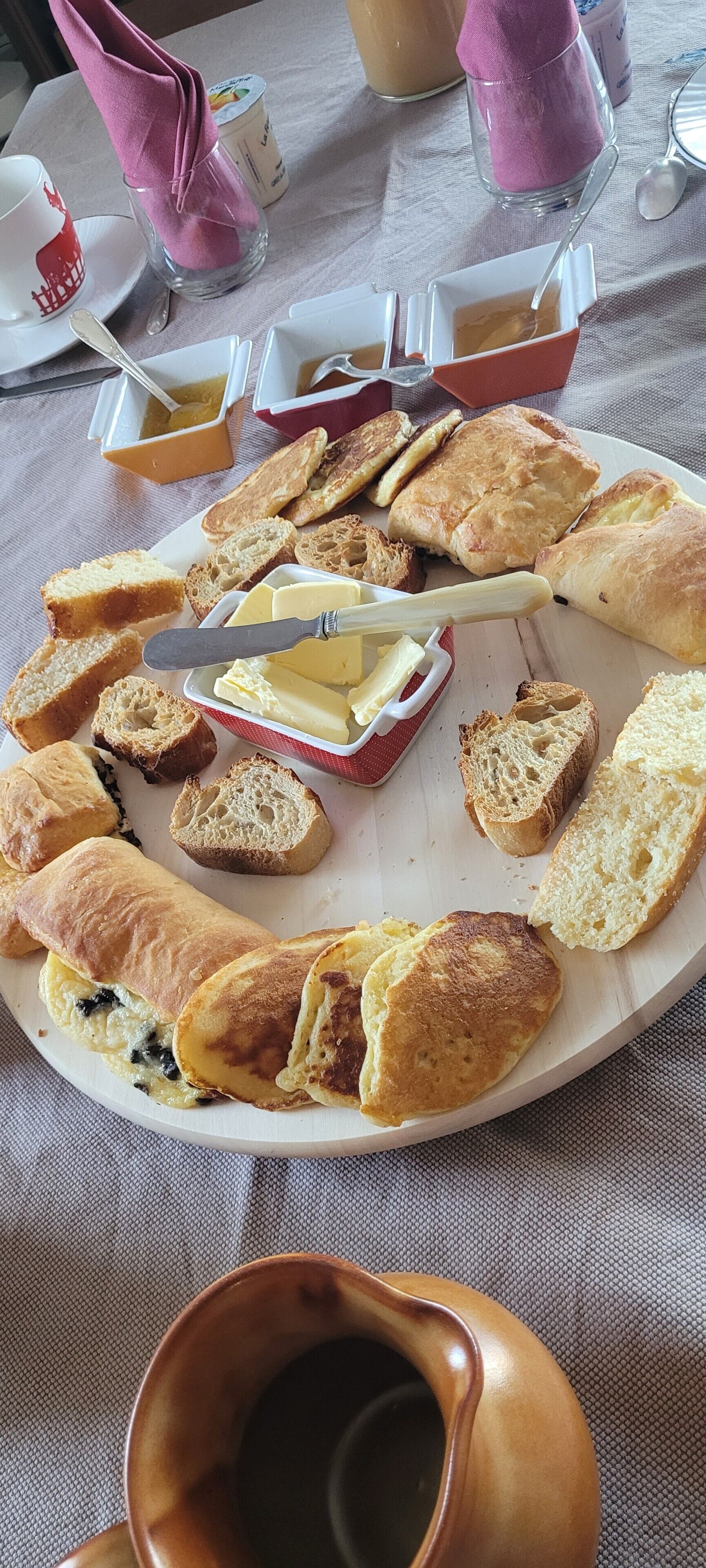 A breakfast platter with various pastries and a knife with butter on a plate.