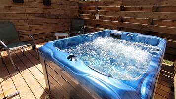 Un bain à remous avec une terrasse en bois et deux chaises.