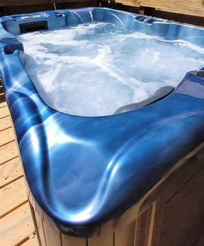 A hot tub with a metallic finish, surrounded by wooden decking.