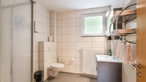 Un baño moderno con inodoro, lavabo y zona de ducha.