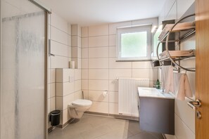 Een moderne badkamer met toilet, wastafel en douche.