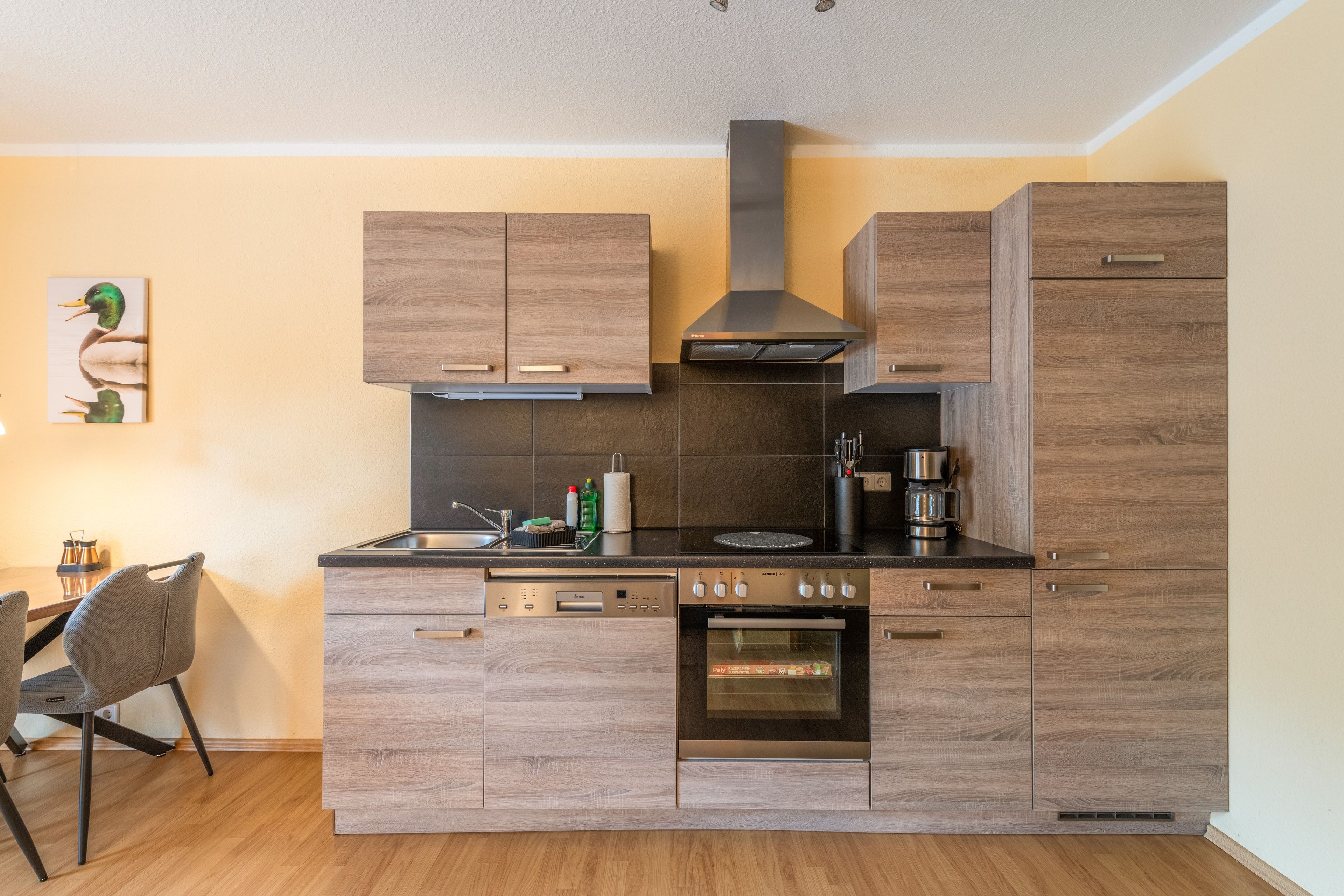 Eine moderne Küche mit Holzschränken, einem Einbauofen und einer Kaffeemaschine.