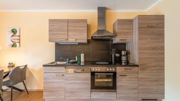 Eine moderne Küche mit Holzschränken, einem Einbauofen und einer Kaffeemaschine.