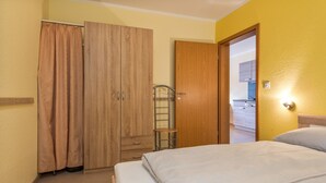 Una habitación de hotel con cama, armario, baño con ducha y kitchenette.