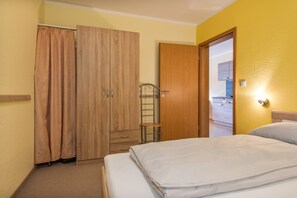Een hotelkamer met een bed, een kledingkast, een badkamer met douche en een kitchenette.