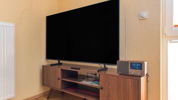 Un televisor de pantalla plana montado sobre un soporte de madera, con un reloj digital que marca las 11:24.