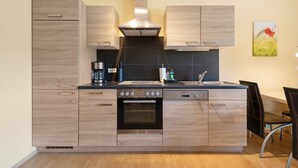 Eine moderne Küche mit Holzschränken, einem eingebauten Ofen und einer Edelstahl-Dunstabzugshaube.