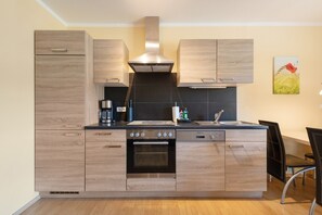 A modern kitchen with wooden cabinetry, a built-in oven, and a stainless steel range hood. - Apartment 'Fewotraum Müritz Möwe 2' with Private Terrace and Wi-Fi (Röbel)
