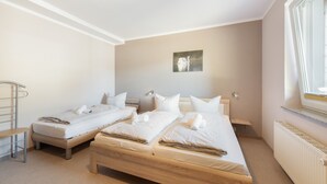 Ein Hotelzimmer mit zwei Einzelbetten, einem kleinen Tisch, einem Heizkörper und einem Fenster mit Vorhängen.
