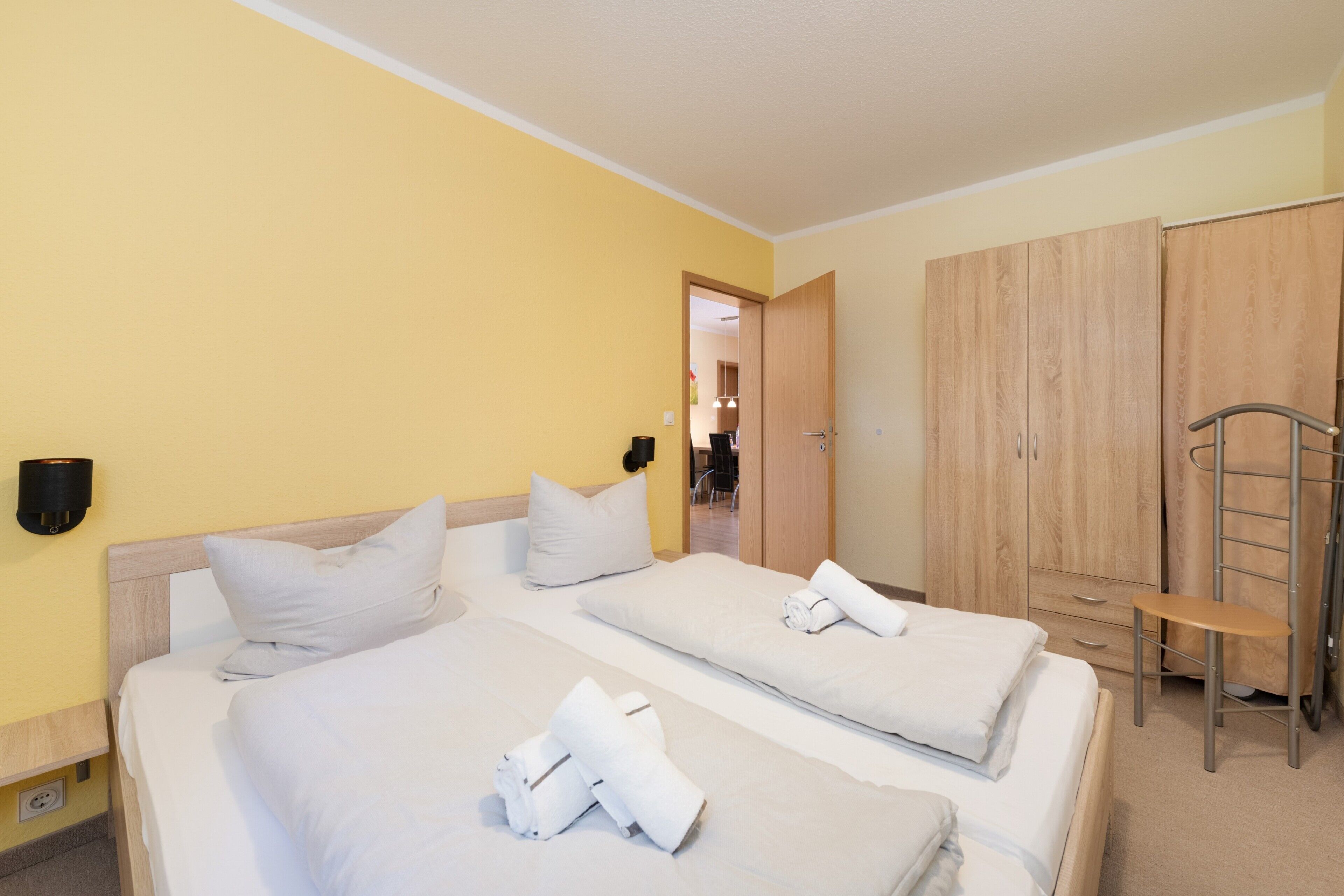 Ein Hotelzimmer mit zwei Betten, einem Kleiderschrank und einem kleinen Tisch.
