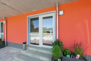 A building entrance with a red wall, a glass door, and steps leading up to it. - Apartment 'Fewotraum Müritz Möwe 2' with Private Terrace and Wi-Fi (Röbel)
