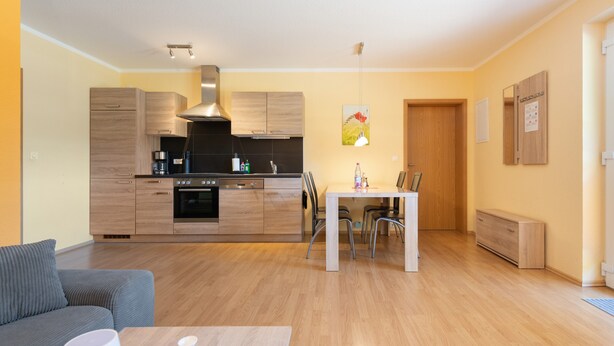 Eine moderne Küche mit Holzschränken, einem eingebauten Backofen und einem Essbereich mit Tisch und Stühlen.