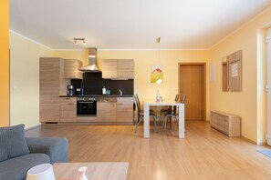 A modern kitchen with wooden cabinets, a built-in oven, and a dining area with a table and chairs.