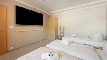 Quarto de hotel com duas camas, televisão, guarda-roupa e uma mesinha.