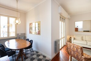 A modern living room with a sofa, a dining table with chairs, a large mirror, and a radiator. - Francesco Terrace apartment (Rome)