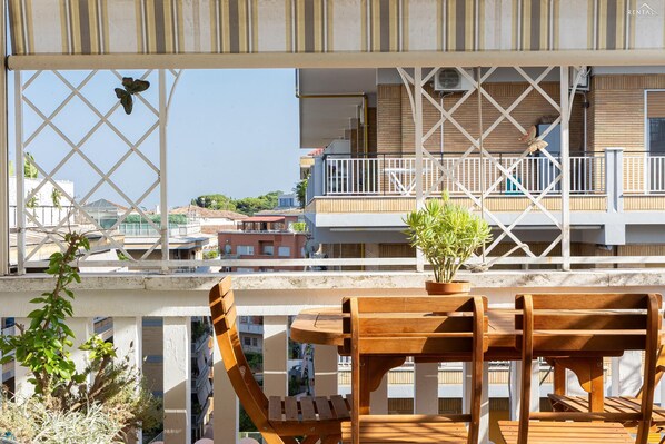Ein Holztisch mit Stühlen auf einem Balkon mit Blick auf eine Wohngegend.