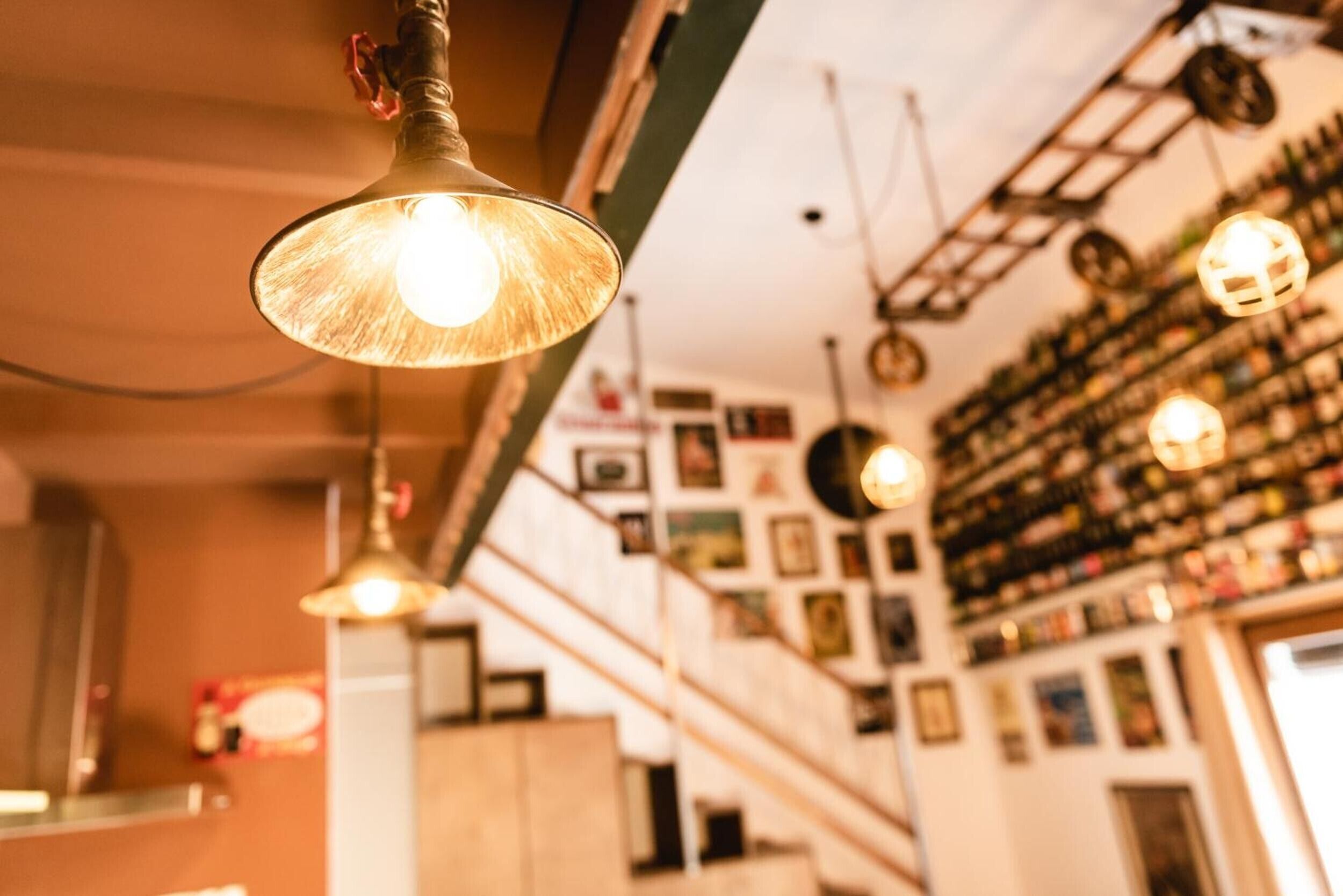 Una habitación con varias lámparas colgantes, una escalera y una pared decorada con cuadros.