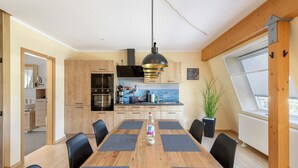 Eine moderne Küche mit Holzschränken, einer schwarzen Mikrowelle und einem Edelstahl-Spülbecken.