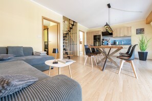 Un salon moderne comprenant un canapé, une table à manger avec des chaises, un coin cuisine et un escalier.