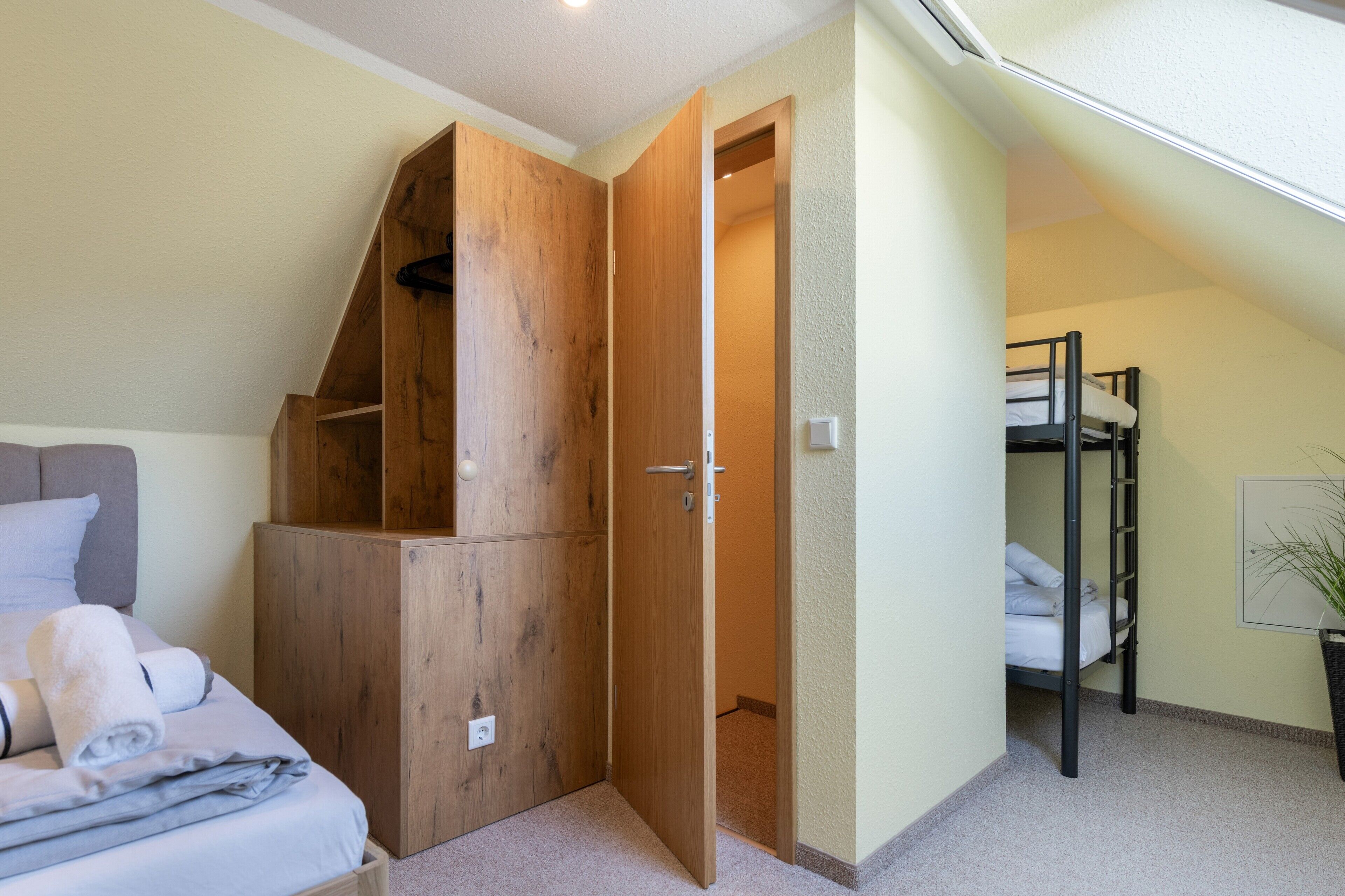 Ein Schlafzimmer mit Etagenbett, einem Holzschrank und einem Bett mit Kissen und einem zusammengerollten Handtuch.