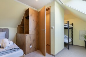 Ein Schlafzimmer mit Etagenbett, einem Holzschrank und einem Bett mit Kissen und einem zusammengerollten Handtuch.
