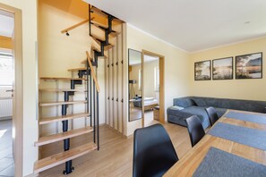 Een modern interieur met een houten trap, een bank en een eettafel.